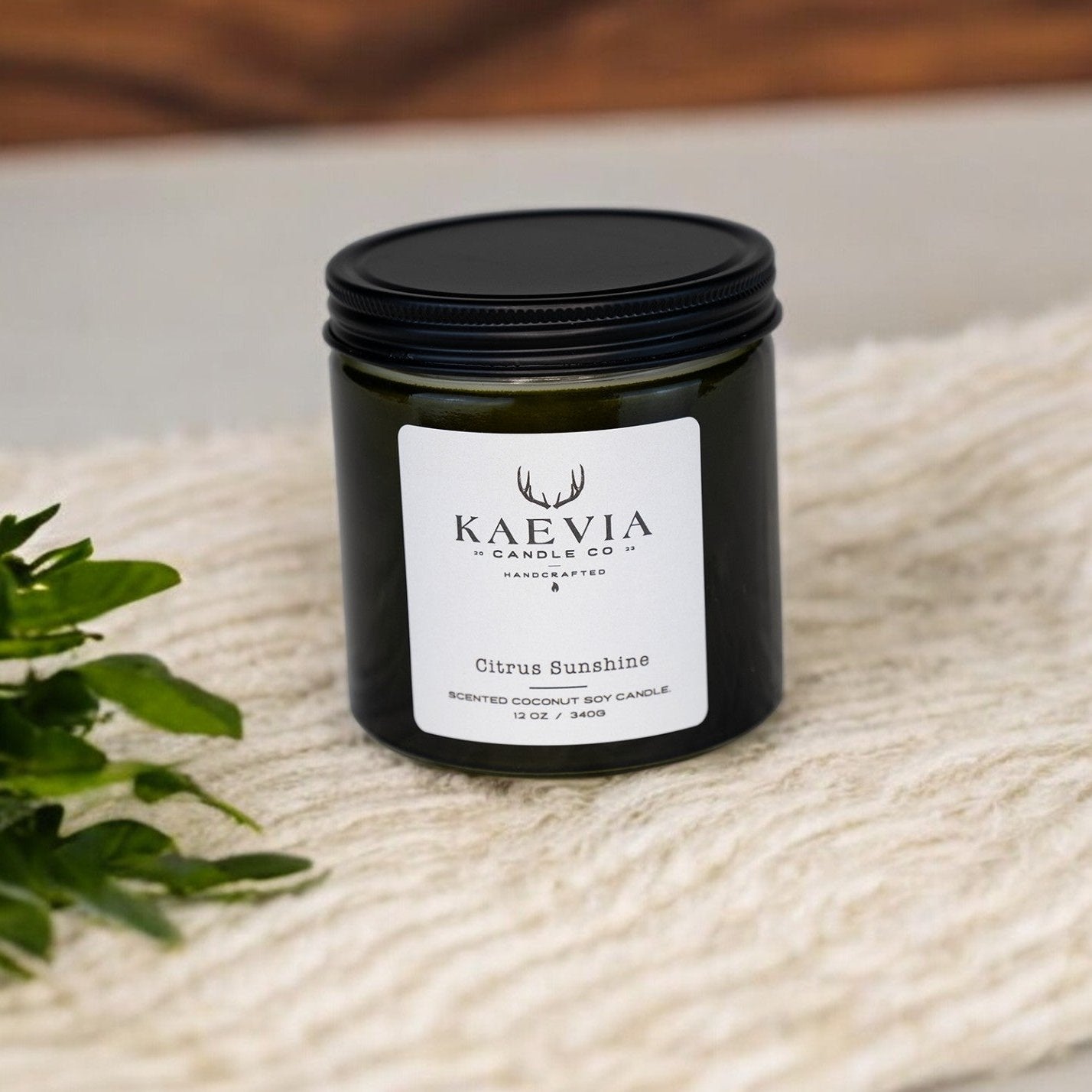 Whitetail candle from Kaevia in green glass jar with black tin lid, surrounded by nature