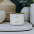 14 oz candle from Kaevia in white cube jar with a wooden lid situated on a table