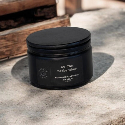 Red Stag Button Buck coconut-soy At The Barbershop candle scent in a black jar with a black lid on concrete