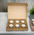 6 small tin jars in a gift boc sitting on a concretetable